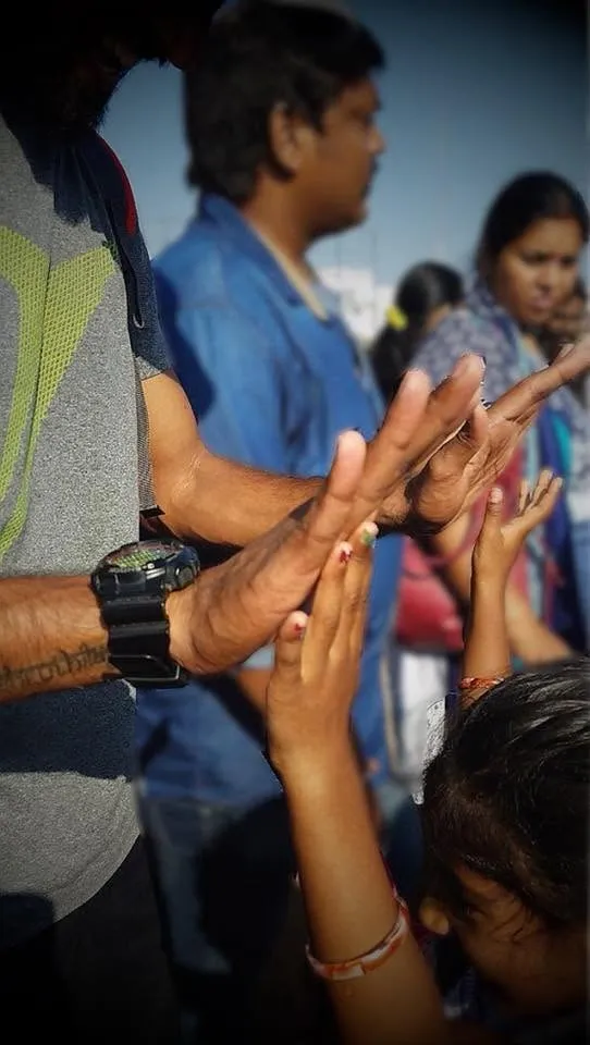 A crowd of people raising their hands together, seen up close in soft daylight