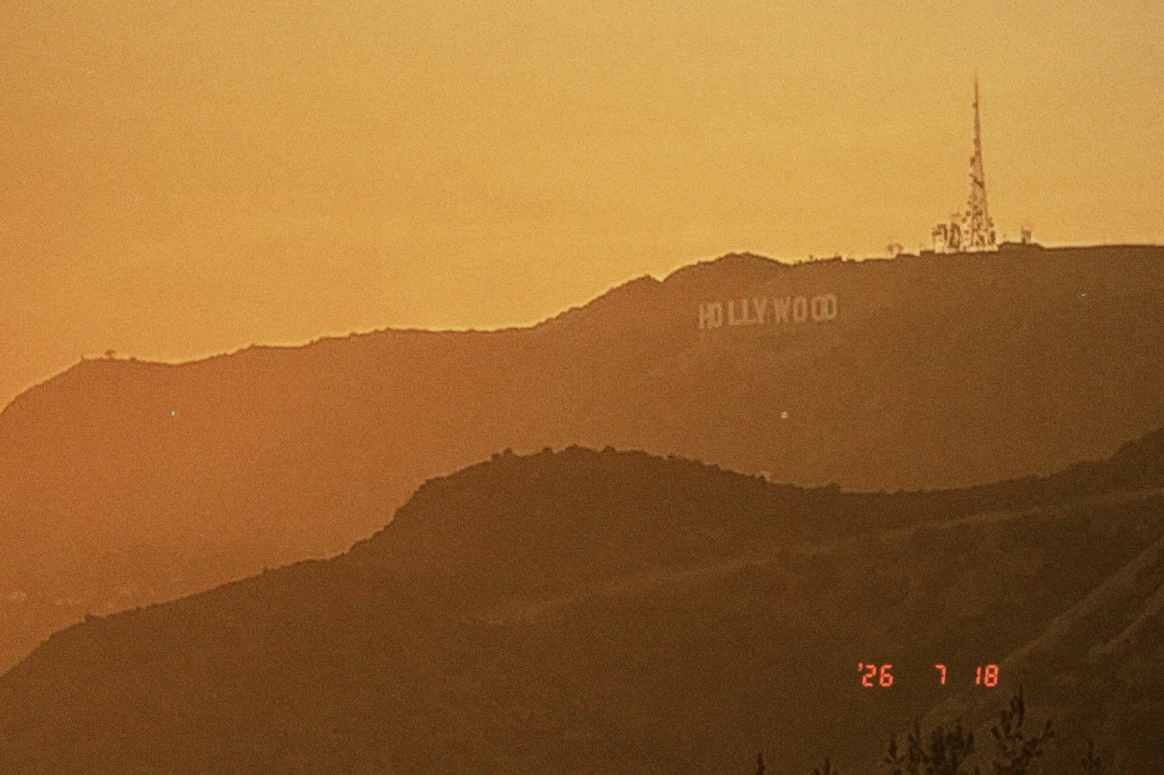Layered hills and the Hollywood sign in deep orange evening haze