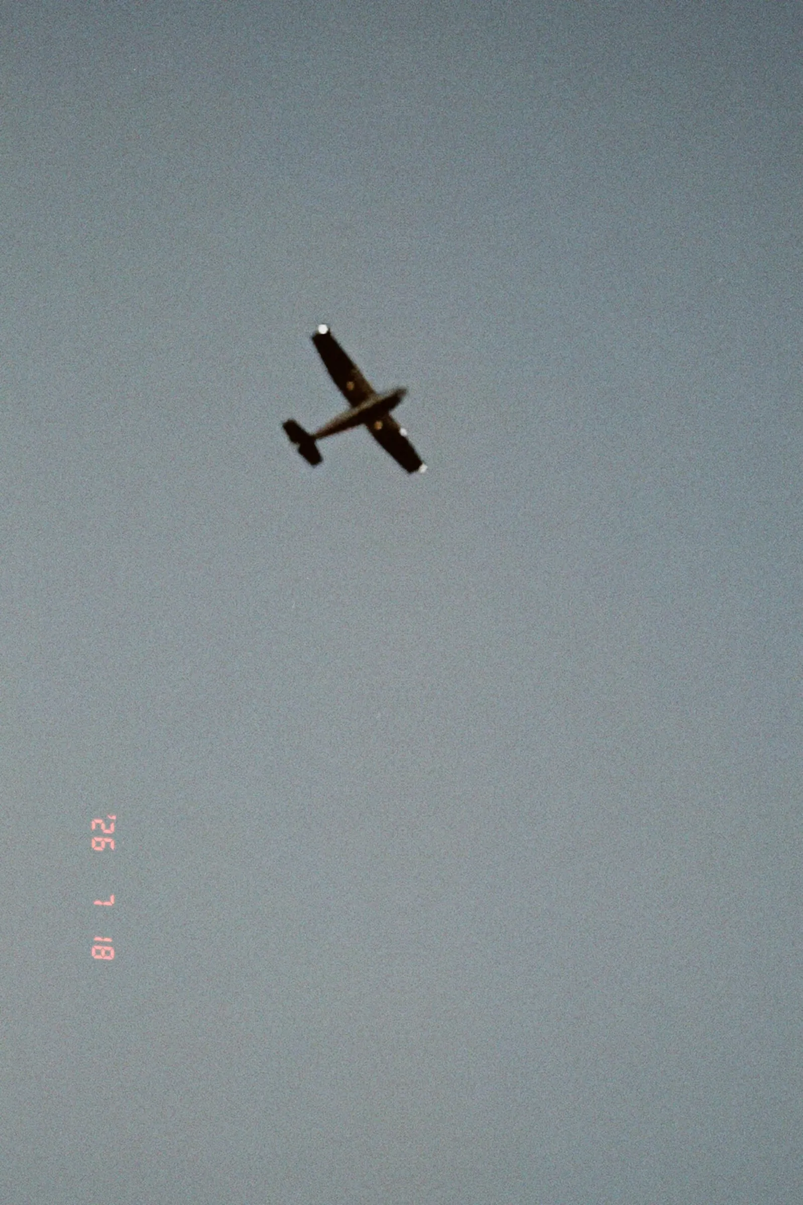 A small propeller plane against a flat gray-blue sky